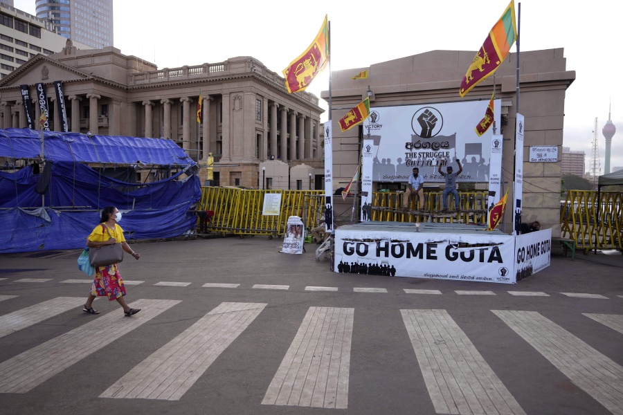 A woman walks past protesters blocking the entrance to presidential secretariat in Colombo, Sri Lanka, Friday, July 15, 2022.