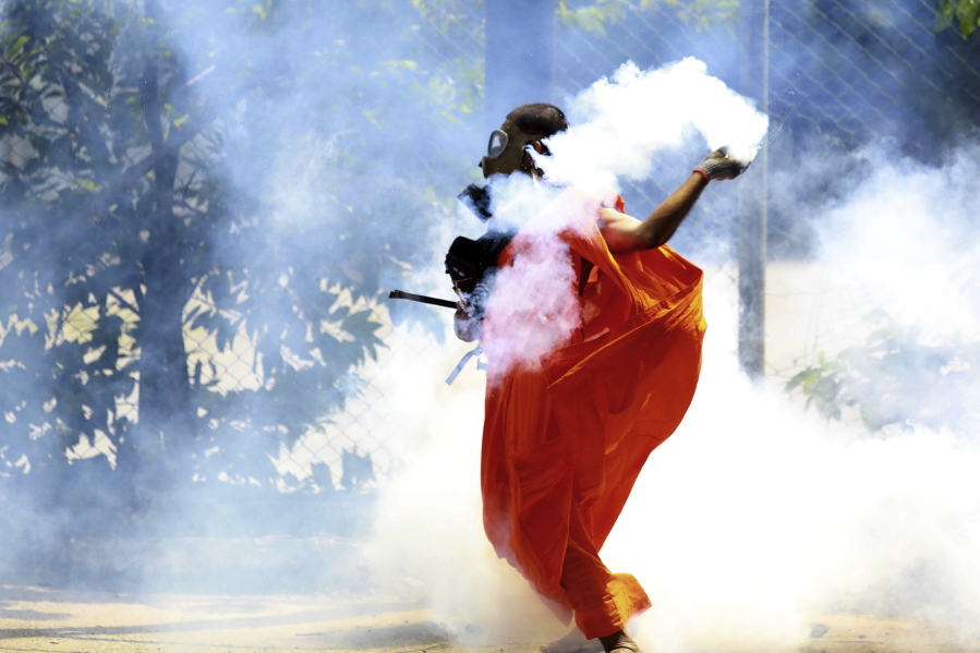 A man throws back a tear gas canister after it was fired by police to disperse protesters in Colombo, Sri Lanka, Saturday, July 9, 2022. Sri Lankan protesters demanding that President Gotabaya Rajapaksa resign forced their way into his official residence on Saturday, a local television report said, as thousands of people took to the streets in the capital decrying the island nation's worst economic crisis in recent memory.