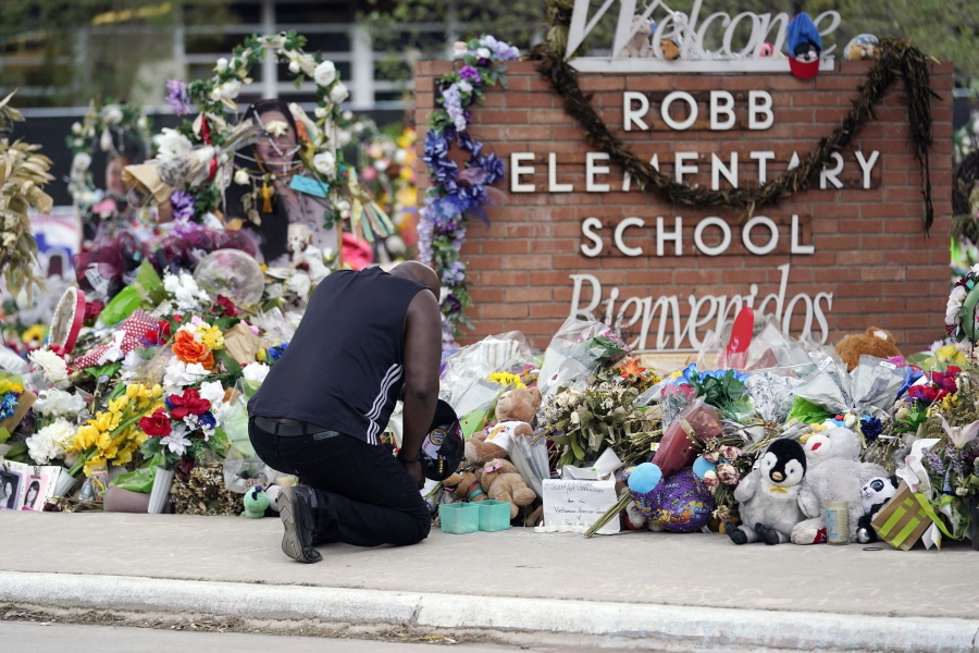 FILE - Reggie Daniels pays his respects a memorial at Robb Elementary School on June 9, 2022, in Uvalde, Texas. Nearly 400 law enforcement officials rushed to the mass shooting that left 21 people dead at the elementary school but "systemic failures" created a chaotic scene that lasted more than an hour before the gunman was finally confronted and killed, according to a report from investigators released Sunday, July 17, 2022.