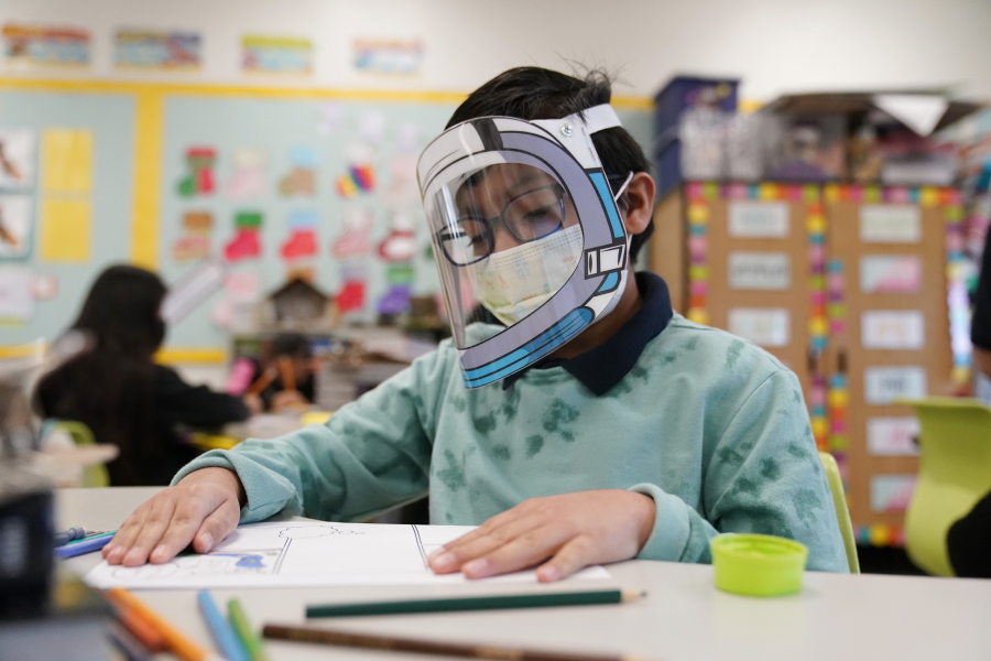 FILE - A student wears a mask and face shield in a 4th grade class amid the COVID-19 pandemic at Washington Elementary School on Jan. 12, 2022, in Lynwood, Calif. As a new school year approaches, COVID-19 infections are again on the rise, fueled by highly transmissible variants, filling families with dread. They fear the return of a pandemic scourge: outbreaks that sideline large numbers of teachers, close school buildings and force students back into remote learning.