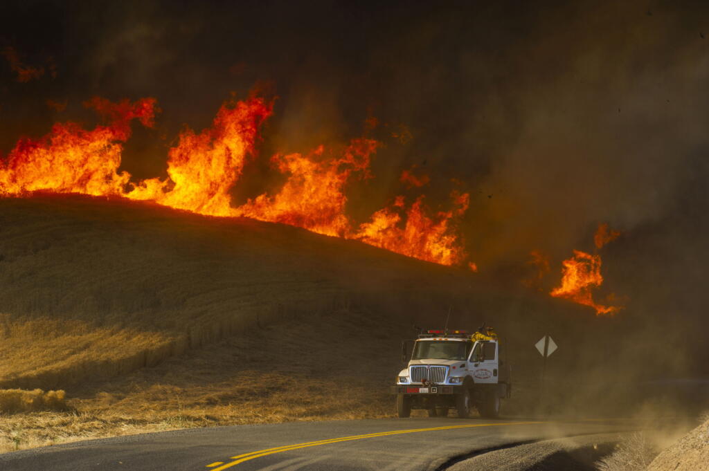 A Walla Walla - Columbia County Joint Fire District #2 truck makes it's way south on Lower Waitsburg Road while battling a massive wheat fire north of Walla Walla, Wash., Friday, July 29, 2022.