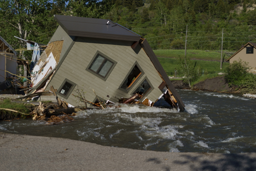 FILE - A house sits in Rock Creek after floodwaters washed away a road and a bridge in Red Lodge, Mont., on June 15, 2022. As cleanup from historic floods at Yellowstone National Park grinds on, climate experts and meteorologists say the gap between the destruction in the area and what was forecast underscores a troublesome trend tied to climate change: Modeling programs used to predict storms aren't keeping up with increasingly extreme weather.