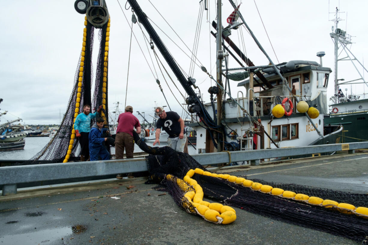 Four men load a fishing net onto a commercial fishing boat at Fishermen's Terminal in Seattle in 2016.