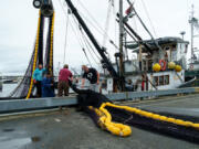 Four men load a fishing net onto a commercial fishing boat at Fishermen's Terminal in Seattle in 2016.