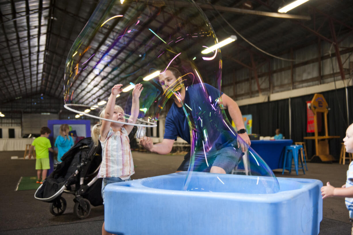 Zayla Tervo, 3, smiles from inside a large bubble made by her father, Bryce Tervo, while her brother, Elijah, 2, at right, watches Saturday at the Wild Science exhibit at the Clark County Fair. The bubble stations were popular attractions at the exhibit in the South Hall.