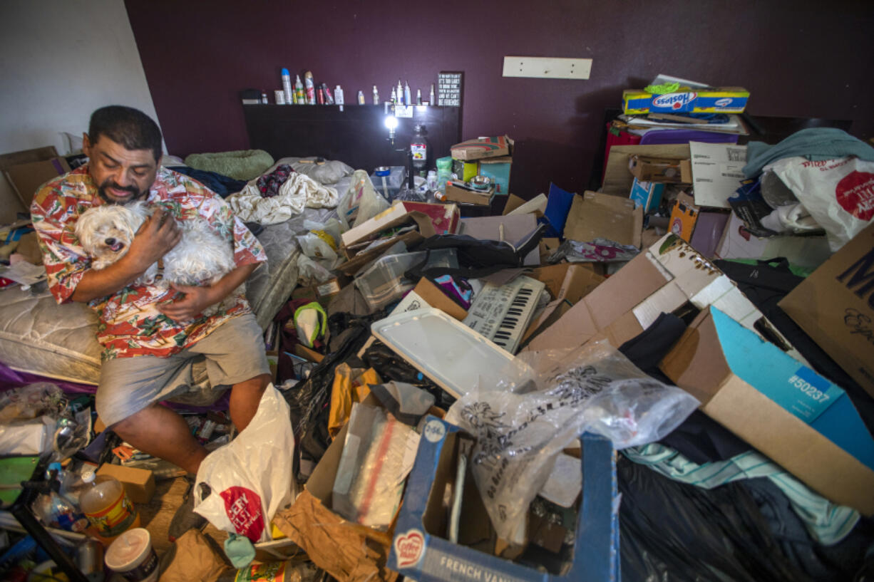 Mario Blanco, 53, with his dog, Leo the Lion, is surrounded by the items he???s been hoarding for a year at the Chateau Inn & Suites on June 30, 2022, in Downey, California.