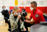 Seattle firefighter and EMT Garth Stroyan administers a COVID-19 vaccination for Asya Strounine, 13, at Nathan Hale High School in Seattle on June 10, 2021.