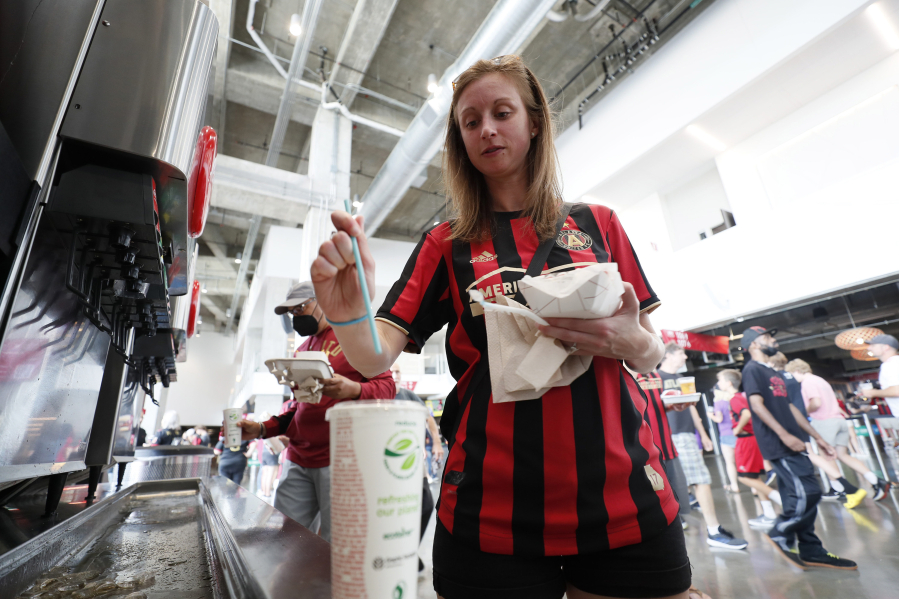 Kate Walton from Atlanta puts a new biodegradable straw into her soft drink at the Mercedes-Benz Stadium on Sunday, July 17, 2022. The new blue drinking straw breaks down in the environment faster than a typical straw.