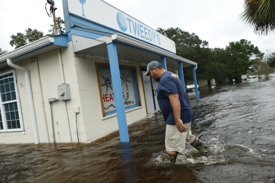 John Tweedy wades into the swift-moving floodwater surrounding his business as he inspects damage in the wake of Hurricane Matthew on October 8, 2016, in McClellanville, South Carolina.