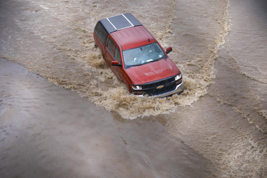 A pickup truck drives through one of the closed lanes on westbound Highway 94 just east of the northbound Interstate 805 due to flooding from the rain, Nov. 28, 2019, in San Diego.