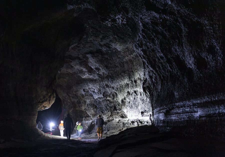 Occasionally it seems as tight as a subway tunnel. Other times it feels as vast as a cathedral. Visitor headlamps and flashlights illuminate the walls of Ape Cave in the Gifford Pinchot National Forest.