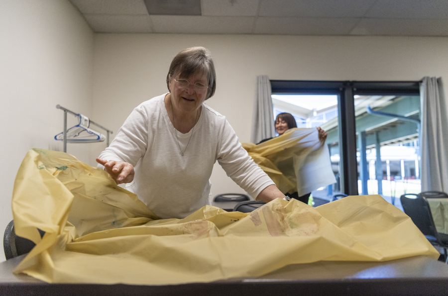 Dairn Woodman, left, and art instructor Margi Russo throw covers onto conference tables Monday at the Luepke Center. Woodman is part of Goodwill's Senior Community Service Employment Program, which trains and employs those older than 55 at nonprofits or government agencies part time.