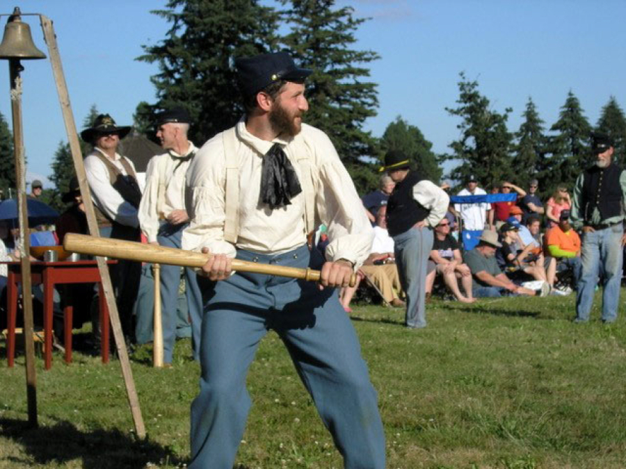 Sports photographers missed capturing the initial 1867 baseball game at Fort Vancouver. This unidentified Sherman Club striker (batter) was caught on camera during a vintage game replay about 150 years later. The umpire called him out if the fielders caught the ball in their bare hands, either in the air or after one bounce. His uniform was all wool -- even the hat -- and hot. His wooden-soled shoes made running the bases slippery.