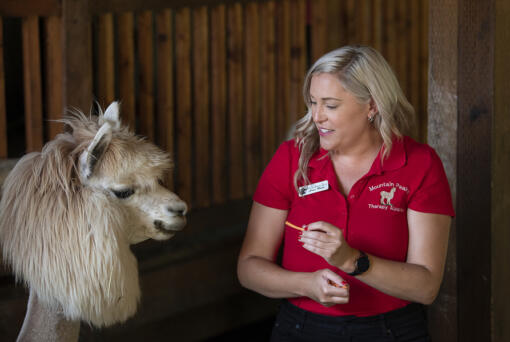 Shannon Joy, co-owner of Mtn Peaks Therapy Llamas & Alpacas, bonds with a four-legged friend on Monday afternoon. The farm trains camelids for therapy and educational purposes. (Amanda Cowan/The Columbian)