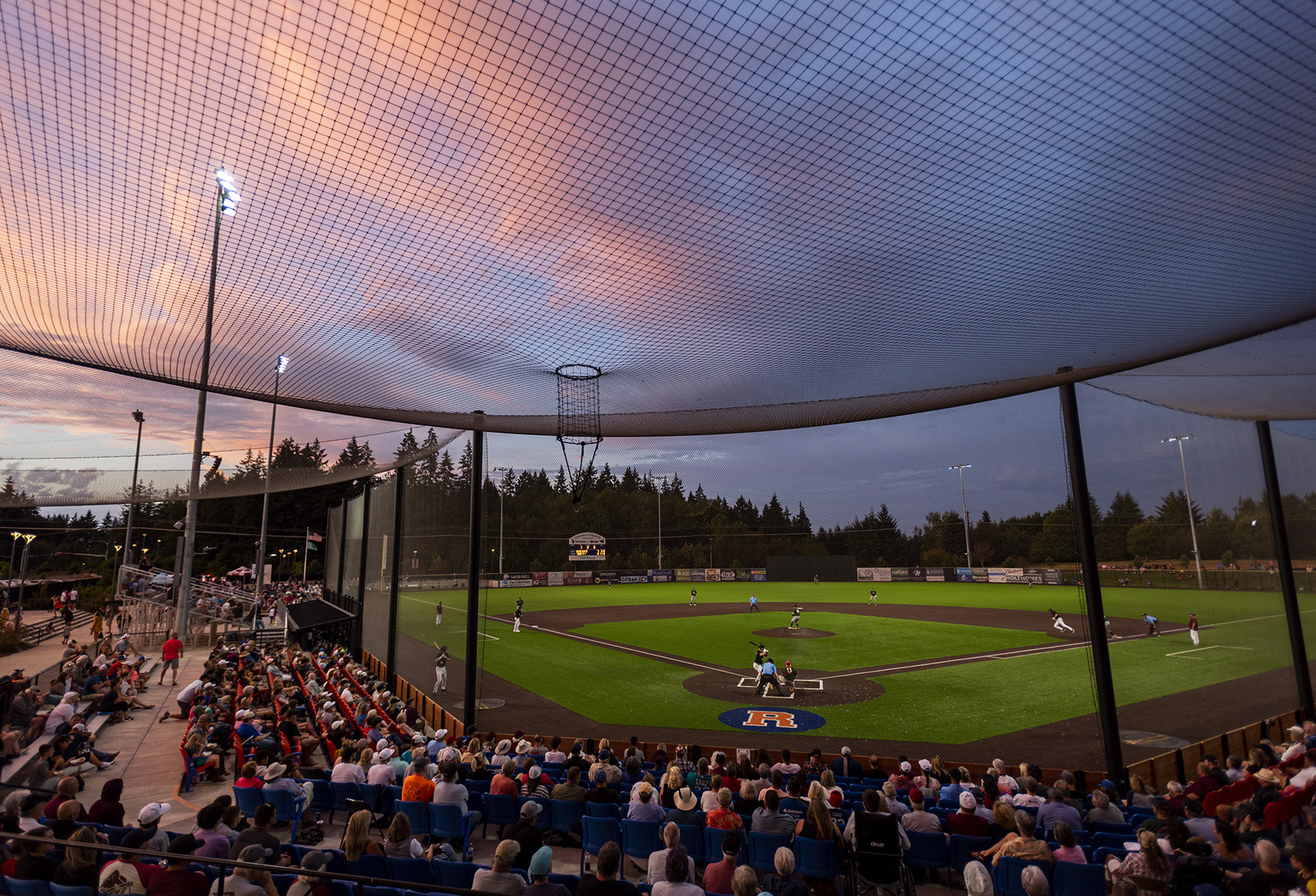 The sun sets over the Ridgefield Outdoor Recreation Complex on Tuesday, Aug. 9, 2022, during a playoff game between the Ridgefield Raptors and the Portland Pickles.