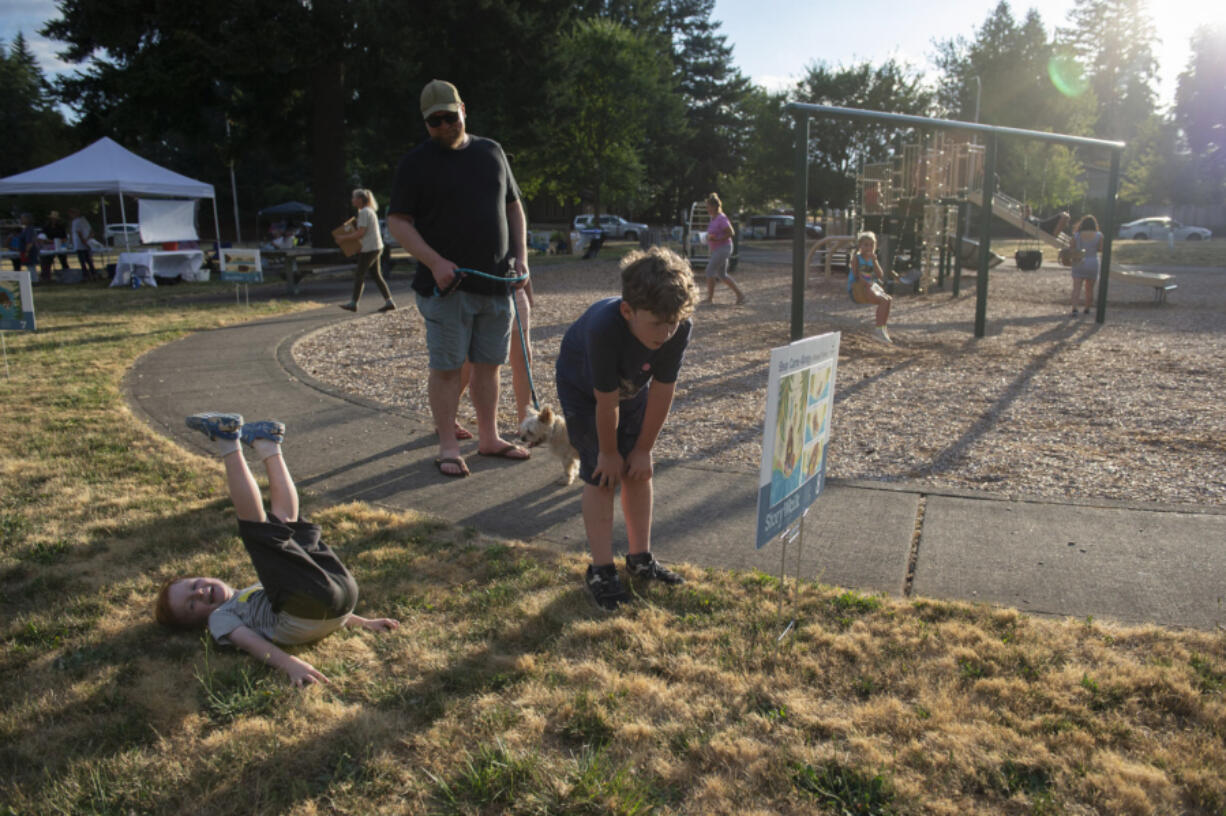 Emmett Reese, 7, and his brother, Cooper, 4, along with their parents, Alena and Spencer Reese of Vancouver, read "Bear Came Along" by Richard T. Morris one page at a time circling the playground at Hearthwood Park.