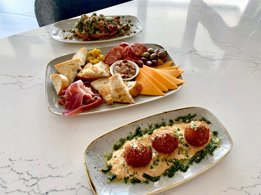AC Lounge focuses on small plates: from back to front, shrimp and pesto toast, fromage and meat board, and cheesy arancini.