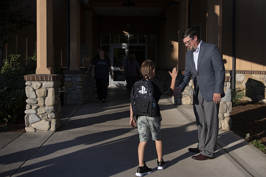 Principal Matthew Fechter shares a high-five with a student while welcoming kids and parents to the first day of school at Fruit Valley Elementary School on Tuesday morning.