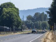 A car drives along Washington State Route 501 as a mirage makes the road appear covered in water on Tuesday, Aug. 30, 2022. Temperatures soared into the upper 90s on Tuesday after a cool weekend and are expected to remain high throughout the week.