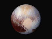 NASA/JHUAPL/SwRI via AP
This image made available by NASA on July 24, 2015, shows a combination of images captured by the New Horizons spacecraft with enhanced colors to show differences in the composition and texture of Pluto's surface. The deep icy basin in Pluto's heart-shaped region may be a natural sinkhole.