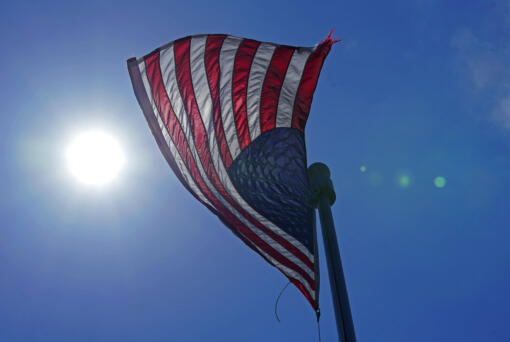 A U.S. flag flies with the sun in the background in downtown Seattle.  (AP Photo/Ted S.