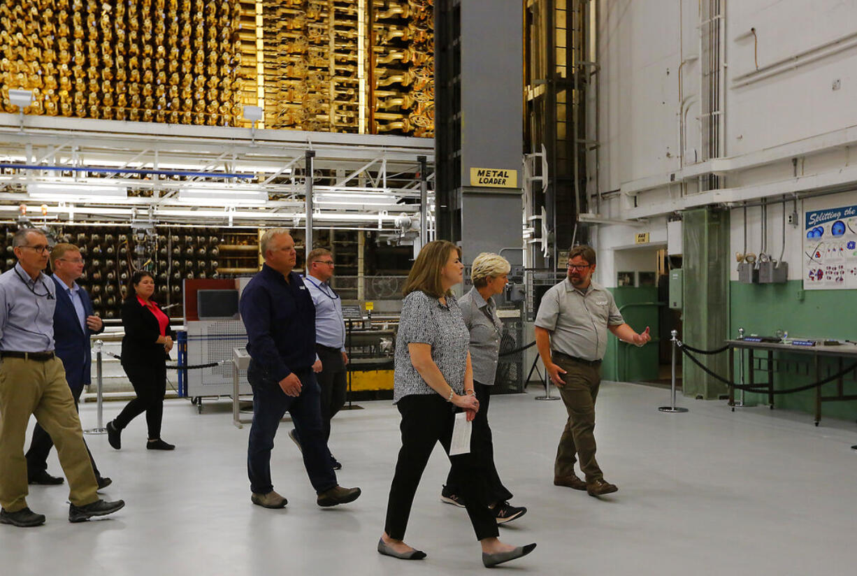 Jennifer Granholm, energy secretary for the U.S. Department of Energy, is guided on her her tour of the historic B Reactor by Colleen French, of the U.S. Department of Energy, and Patrick Jaynes, B Reactor operations manager, Friday, Aug. 12, 2022, while visiting the Hanford Nuclear Site near Richland, Wash. The face of the nuclear reactor, which was used during World War II to develop the nuclear bomb, is visible behind the group. The historic location is part of the Manhattan Project National Historic Park.