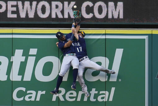 Seattle Mariners center fielder Julio Rodriguez, left, and right fielder Mitch Haniger collide at the wall while trying to catch a fly ball from Los Angeles Angels' Luis Rengifo during the first inning of a baseball game Monday, Aug. 15, 2022, in Anaheim, Calif. Rengifo was awarded a solo home run on the play.