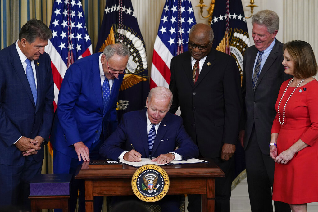 President Joe Biden signs the Democrats' landmark climate change and health care bill in the State Dining Room of the White House in Washington, Tuesday, Aug. 16, 2022, as from left, Sen. Joe Manchin, D-W.Va., Senate Majority Leader Chuck Schumer of N.Y., House Majority Whip Rep. James Clyburn, D-S.C., Rep. Frank Pallone, D-N.J., and Rep. Kathy Castor, D-Fla., watch.