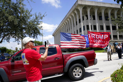 A vehicle with flags in support of Donald Trump drives outside of the Paul G. Rogers Federal Courthouse, Thursday, Aug. 18, 2022, in West Palm Beach, Fla. Attorneys for the nation's largest media companies are presenting their case before a federal magistrate judge to make public the affidavit supporting the warrant that allowed FBI agents to search former President Donald Trump's Mar-a-Lago estate in Florida.