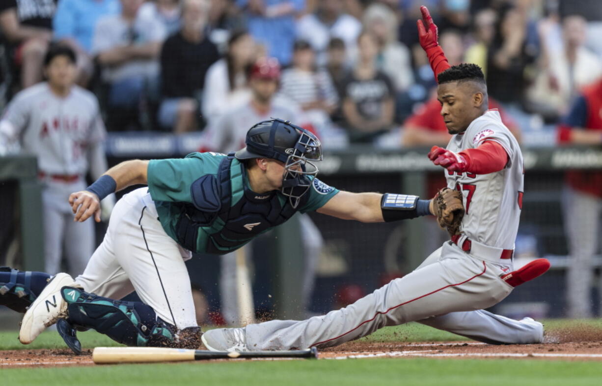 Seattle Mariners catcher Cal Raleigh tags out Los Angeles Angels' Magneuris Sierra at home plate after Sierra attempted to stretch a triple to an inside-the-park home run during the second inning of a baseball game Friday, Aug. 5, 2022, in Seattle.