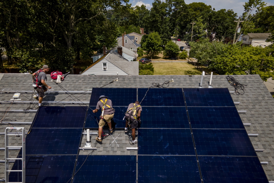 FILE - Employees of NY State Solar, a residential and commercial photovoltaic systems company, install an array of solar panels on a roof, Thursday, Aug. 11, 2022, in the Long Island hamlet of Massapequa, N.Y.  Americans are less concerned now about how climate change might impact them personally -- and about how their personal choices affect the climate than they were three years ago, according to a according to a June poll from The Associated Press-NORC Center for Public Affairs Research.