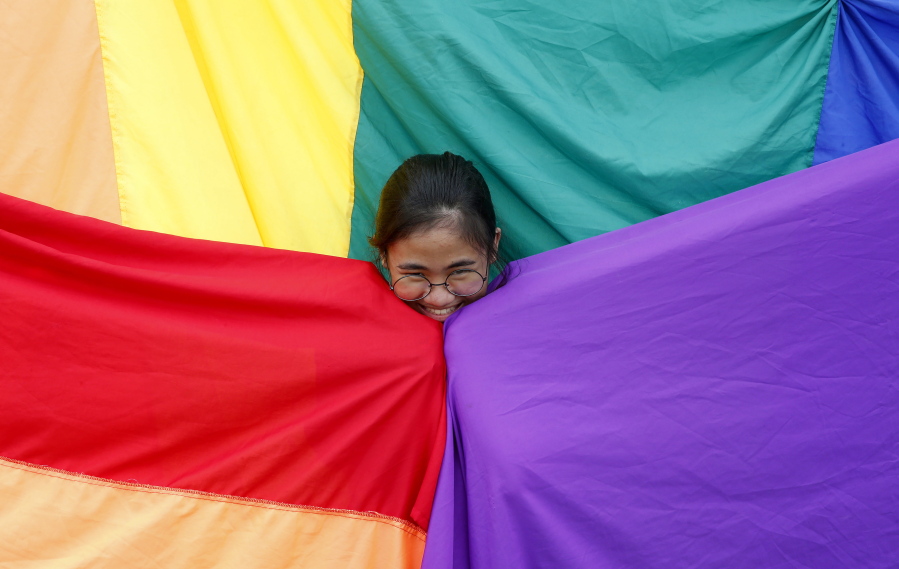 FILE - A supporter of the Philippine LGBT (Lesbians Gays Bisexual Transgender) group poses before the rainbow flag during the annual celebration of "Pride March" June 30, 2018, in Marikina city, east of Manila, Philippines. Singapore's announcement Sunday, Aug. 22, 2022, that it would decriminalize sex between men is being hailed as a step in the right direction for LGBTQ rights in the Asia-Pacific region, a vast area of nearly 5 billion people with different laws and attitudes.
