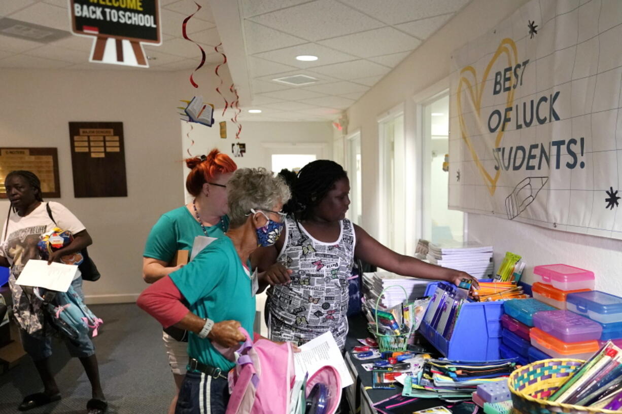 Aaliyah Floyd, 10, right, selects school supplies with volunteer Cindy Blomquist, left, at the annual Back to School Distribution Day at The Pantry, Friday, July 29, 2022, in Fort Lauderdale, Fla. The Pantry works with grandparents who are the primary caregivers for their grandchildren, offering free backpacks, lunch boxes, school supplies and sneakers. This back-to-school shopping season, parents, particularly in the low to middle income bracket, are focusing on the basics, trading down to cheaper stores and stretching out their buying as surging inflation takes a toll on their household budgets.