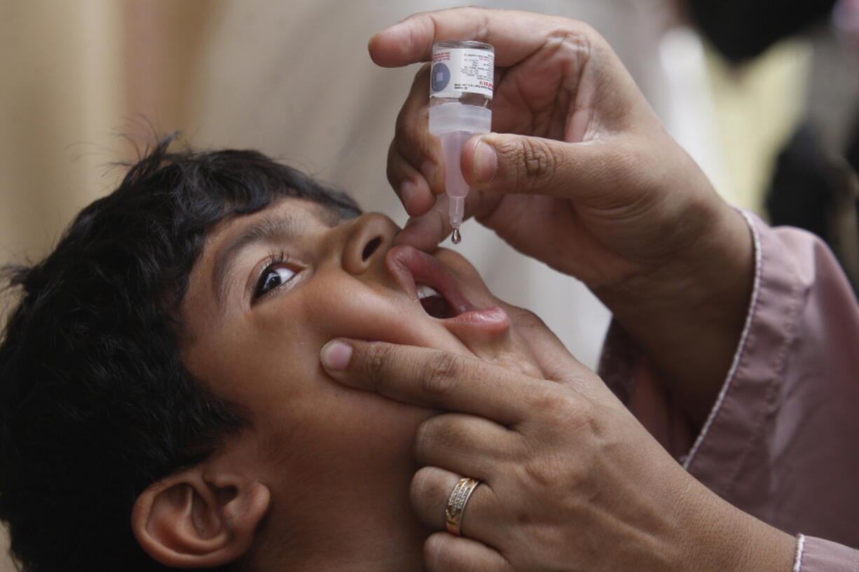 FILE - A health worker gives a polio vaccine to a child in Karachi, Pakistan, May 23, 2022. British health authorities on Wednesday, Aug. 10 say they will offer a polio booster dose to children aged 1 to 9 in London, after finding evidence the virus has been spreading in multiple regions of the capital, despite not confirming any cases of the paralytic disease in people.