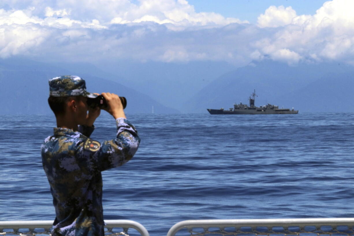 FILE - In this photo provided by China's Xinhua News Agency, a People's Liberation Army member looks through binoculars during military exercises as Taiwan's frigate Lan Yang is seen at the rear on Aug. 5, 2022. China on Wednesday, Aug. 10, reaffirmed its threat to use military force to bring self-governing Taiwan under its control, amid threatening Chinese military exercises that have raised tensions between the sides to their highest level in years.