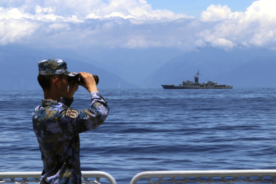 In this photo provided by China'??s Xinhua News Agency, a People's Liberation Army member looks through binoculars during military exercises as Taiwan'??s frigate Lan Yang is seen at the rear, on Friday, Aug. 5, 2022. China is holding drills in waters around Taiwan in response to a recent visit by U.S. House Speaker Nancy Pelosi.