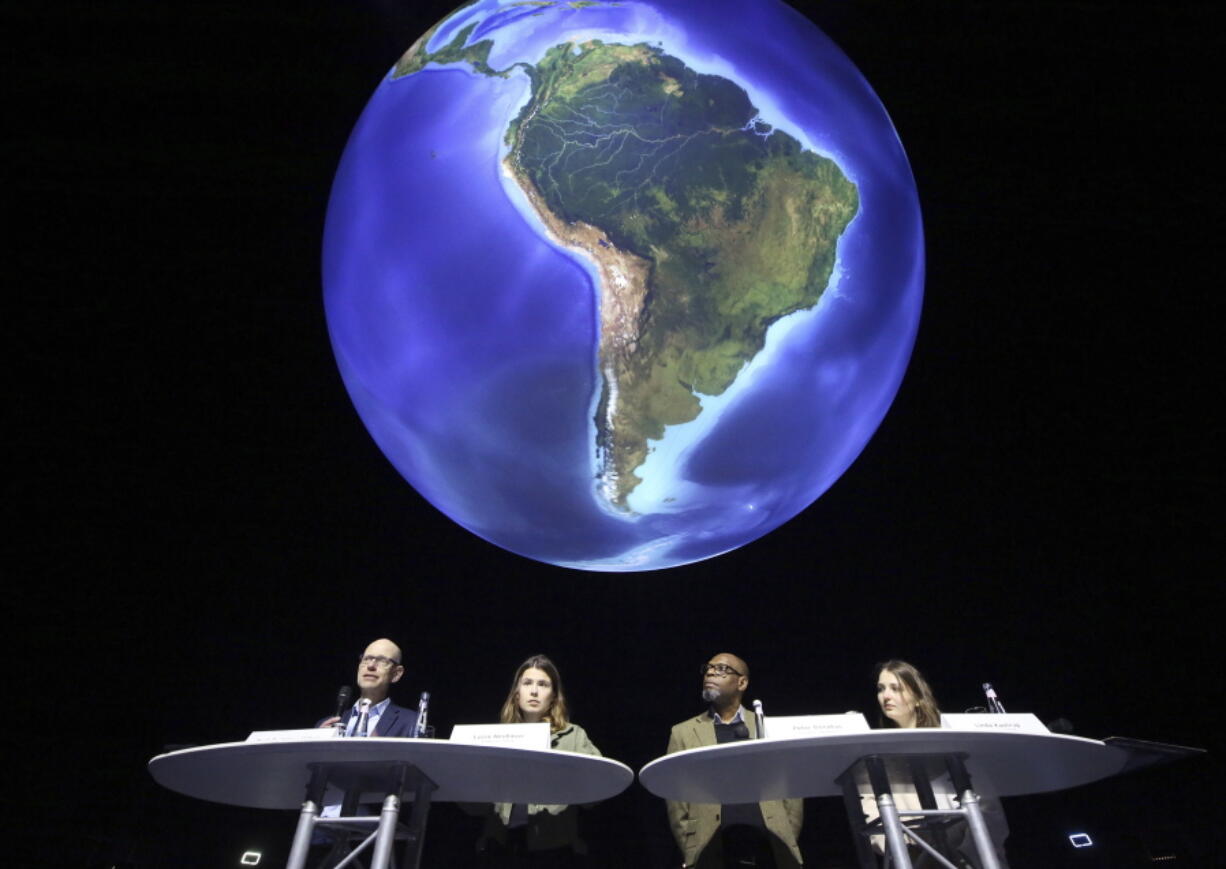 FILE - Niklas Hoehne, from left, New Climate Institute Cologne, Luisa Neubauer, Fridays for Future activist, Peter Donatus, journalist and activist, and Linda Kastrop, activist, stand in front of a giant globe in the exhibition "The Fragile Paradise" during a news conference on planned actions in 2022 and discuss "greenwashing" in Brussels, Oberhausen, Germany, Feb. 11, 2022. The U.S. has renewed legitimacy on global climate issues and will be able to inspire other nations in their own emissions-reducing efforts, experts said, after the Democrats pushed their big economic bill through the Senate on Sunday, Aug. 7, 2022. Climate activists agree that the bill is just one step on a larger path towards climate action.