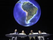 FILE - Niklas Hoehne, from left, New Climate Institute Cologne, Luisa Neubauer, Fridays for Future activist, Peter Donatus, journalist and activist, and Linda Kastrop, activist, stand in front of a giant globe in the exhibition "The Fragile Paradise" during a news conference on planned actions in 2022 and discuss "greenwashing" in Brussels, Oberhausen, Germany, Feb. 11, 2022. The U.S. has renewed legitimacy on global climate issues and will be able to inspire other nations in their own emissions-reducing efforts, experts said, after the Democrats pushed their big economic bill through the Senate on Sunday, Aug. 7, 2022. Climate activists agree that the bill is just one step on a larger path towards climate action.