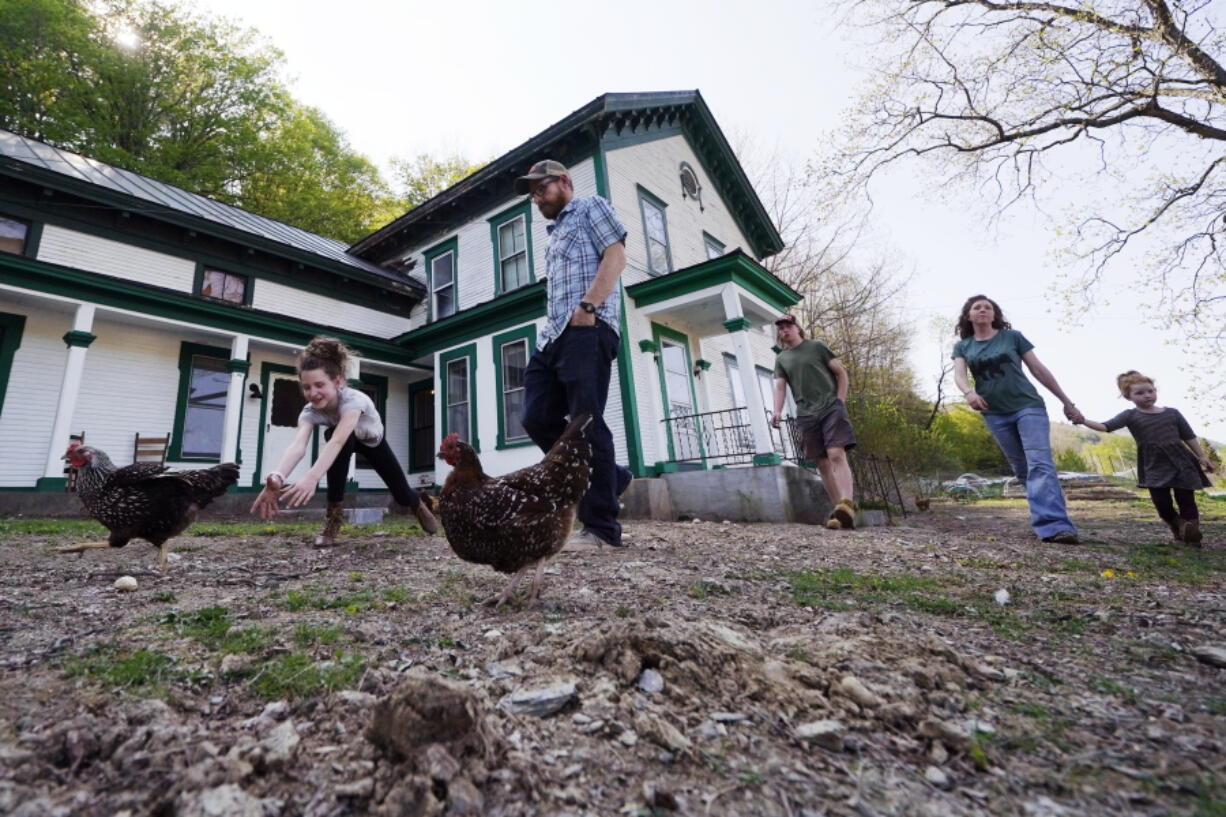 Soraya Holden, left, chases a chicken while walking with her family past their family home, Thursday, May 12, 2022, in Proctor, Vt. After fleeing one of the most destructive fires in California, the Holden family wanted to find a place that had not been so severely affected by climate change and chose Vermont.