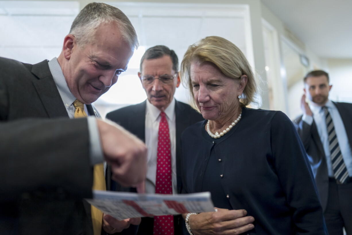From left, Sen. Dan Sullivan, R-Alaska, Sen. John Barrasso, R-Wyo., and Sen. Shelley Moore Capito, R-W.Va., confer just before a news conference to discuss their efforts to rescind recent Biden administration rules on the National Environmental Policy Act, at the Capitol in Washington, Tuesday, Aug. 2, 2022. (AP Photo/J.