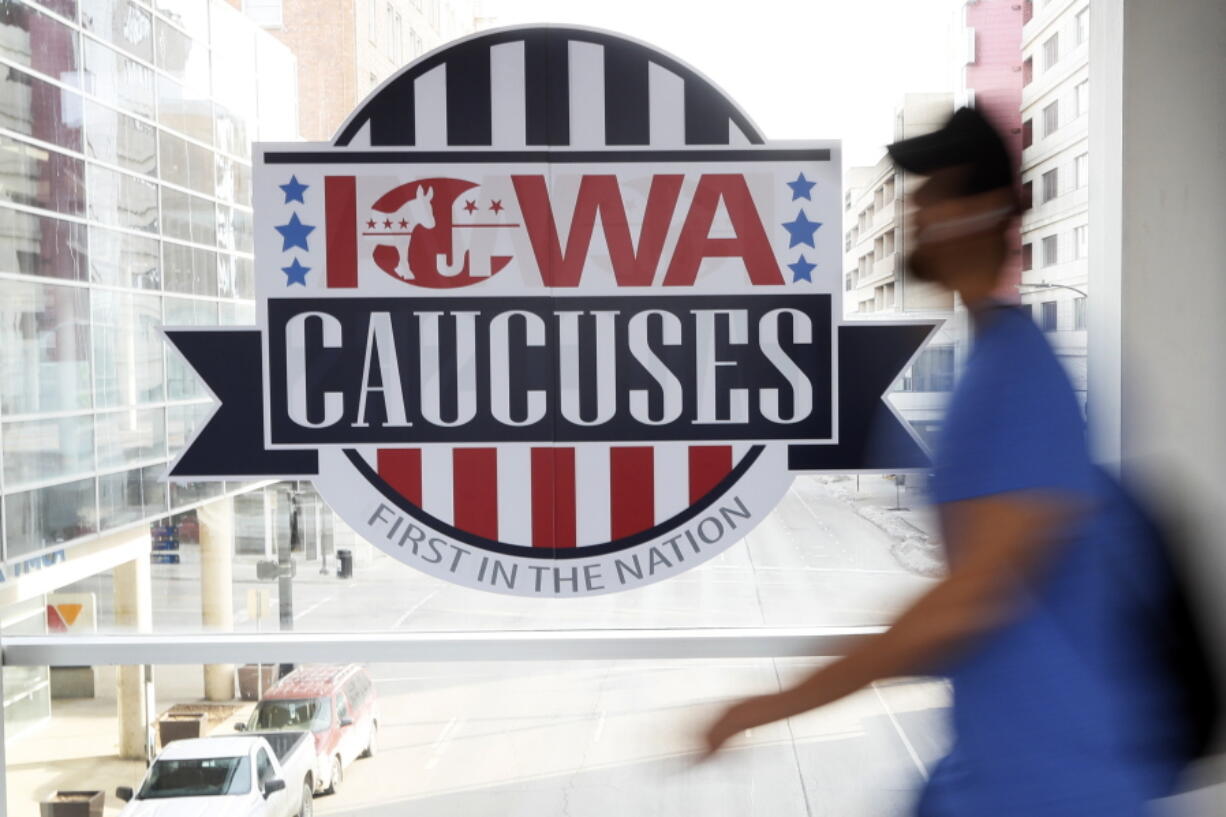 FILE - A pedestrian walks past a sign for the Iowa Caucuses on a downtown skywalk, in Des Moines, Iowa, on Feb. 4, 2020. Democrats may be moving toward shaking up their presidential nominating process starting in 2024. They're poised to boot Iowa from the lead-off spot as part of a broader effort to allow to go earlier less overwhelmingly white states that better reflect the party's diverse electorate.