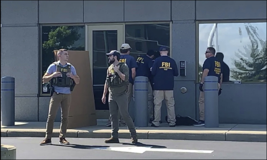 In this image taken from FOX19 Cincinnati video, FBI officials gather outside the FBI building in Cincinnati, Thursday, Aug. 11, 2022. An armed man decked out in body armor tried to breach a security screening area at the FBI field office in Ohio on Thursday, then fled and exchanged gunfire in a standoff with law enforcement, authorities said.