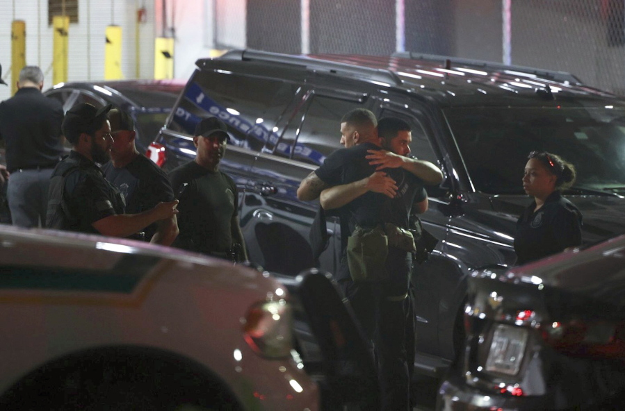 Police officers and other officials embrace while standing outside the Ryder Trauma Center after a Miami-Dade police officer was shot in an exchange of gunfire during a car chase with an armed robbery suspect, Monday, Aug. 15, 2022, in Miami.