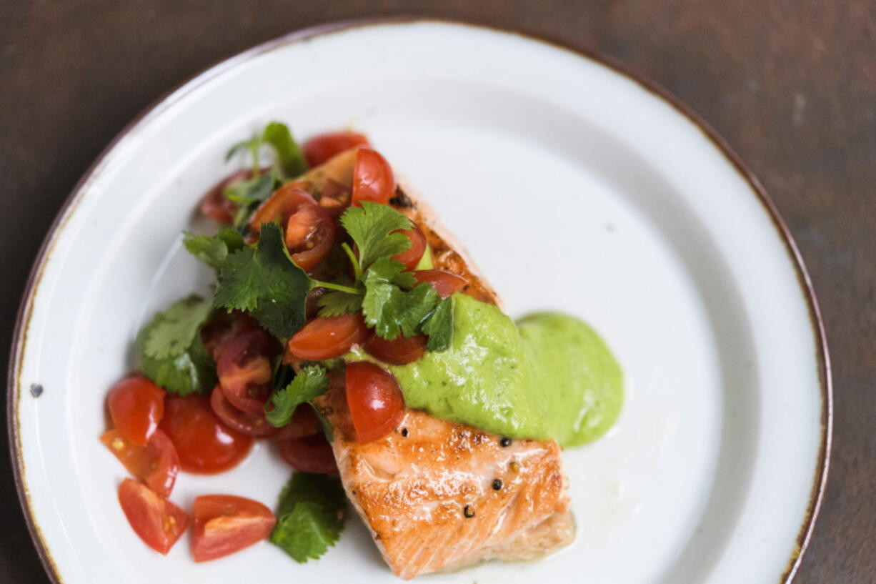 This image released by Milk Street shows a recipe for salmon with avocado sauce and tomato-cilantro salsa.