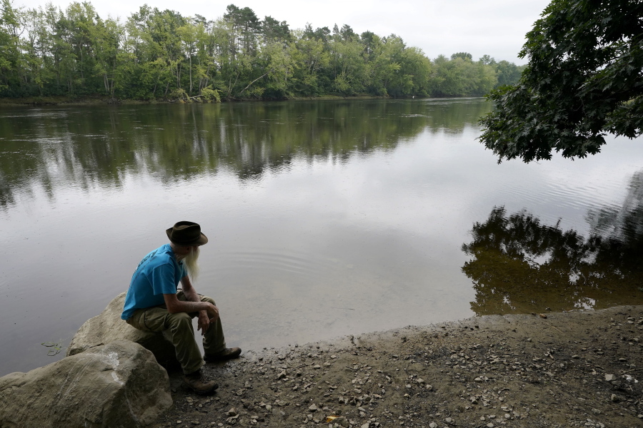 FILE -- David Lidstone, 81, sits near the Merrimack River on Aug. 10, 2021, in Boscawen, N.H. Lidstone, a former hermit who a year ago was forced to leave his New Hampshire compound after two decades, has found a new home in Maine.