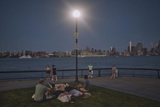 FILE - People spend time at the park at dusk during a summer heat wave, July 21, 2022, in Hoboken, N.J. The continental United States in July set a record for overnight warmth, providing little relief from the day's sizzling heat for people, animals, plants and the electric grid, meteorologists said.