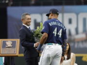 Former Seattle Mariners player Ichiro Suzuki, left, is presented with a bouquet of flowers by Mariners' Julio Rodriguez as he is inducted into the Mariners Hall of Fame during a ceremony before a baseball game between the Mariners and the Cleveland Guardians, Saturday, Aug. 27, 2022, in Seattle.