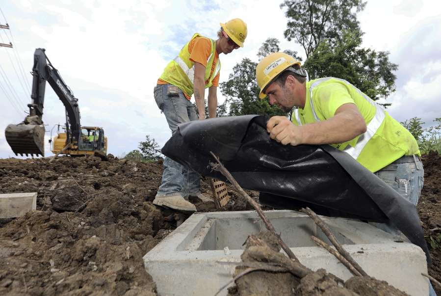 Taylor Purdy, right, a pipe layer with Complete General Construction, and colleague Adam Clary install temporary silt protection for a catch basin near the new Intel semiconductor manufacturing plant construction site in Johnstown, Ohio, Friday, Aug. 5, 2022. Ohio's largest-ever economic development project comes with a big employment challenge: how to find 7,000 construction workers in an already booming building environment when there's also a national shortage of people working in the trades.