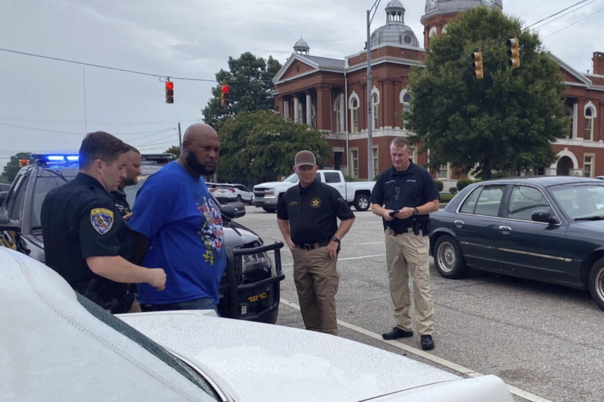 This photo provided by Troup County Sheriff's Office police take Jerel Raphael Brown into custody on Aug. 17, 2022 in LaFayette, Ala.  Brown, 39, of Montgomery was arrested without incident Wednesday near the courthouse in LaFayette with more than 2,000 rounds of ammunition and an alarming number of firearms in his 1996 white Cadillac Fleetwood, police said.
