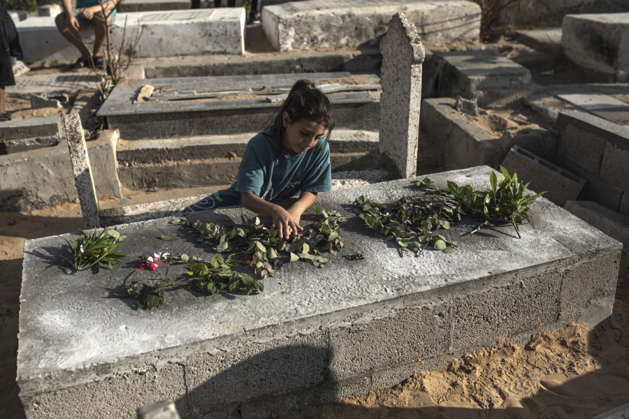 A Palestinian girl lays roses on the grave of one of the children of Nijim family at Al-Faluja cemetery in Jabalia in the northern Gaza Strip, Tuesday, Aug. 16, 2022.